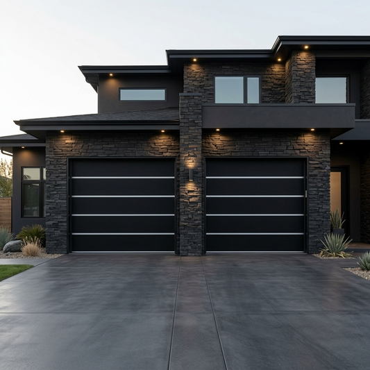 Two modern black garage doors installed on a contemporary dark gray house with stone veneer columns and a concrete driveway at dusk.